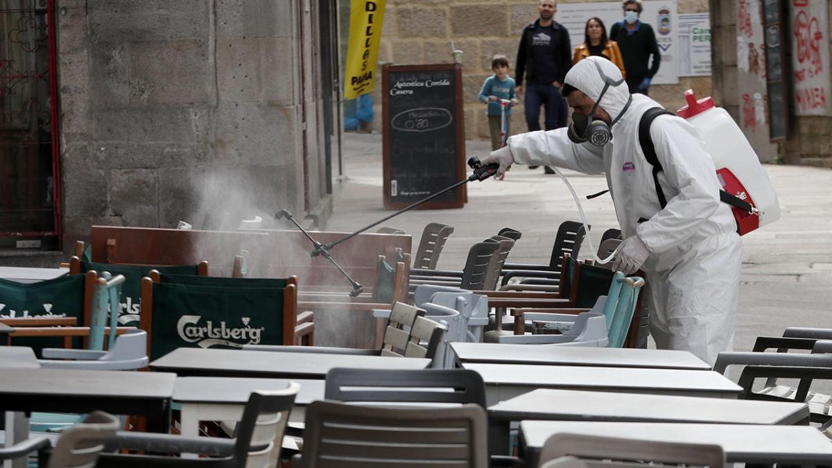 Un hombre realizando tareas de desinfección en una terraza. // Jose Lores