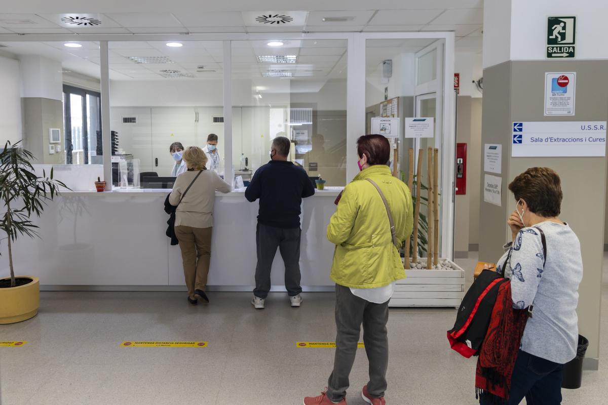 Personas esperando para ser atendidas en el mostrador de un centro de salud de València.
