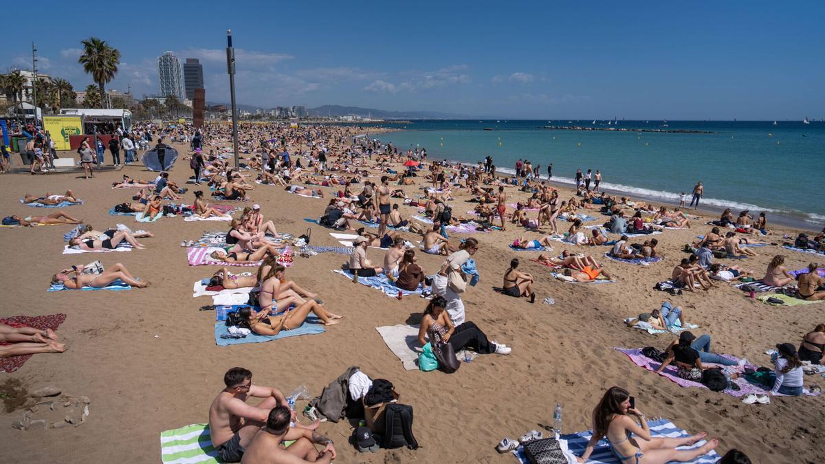 Turistas difrutando del sol y la playa en Barcelona.