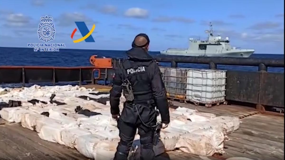 Uno de los policías nacionales del cuerpo de operaciones especiales custodia la droga en el mercante, con el buque &#039;Tornado&#039; al fondo, antes de llegar a Vigo.