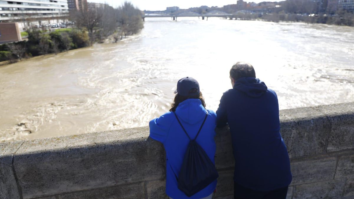 Dos personas observan el caudal del río Ebro desde el puente de Piedra de Zaragoza en una imagen de archivo