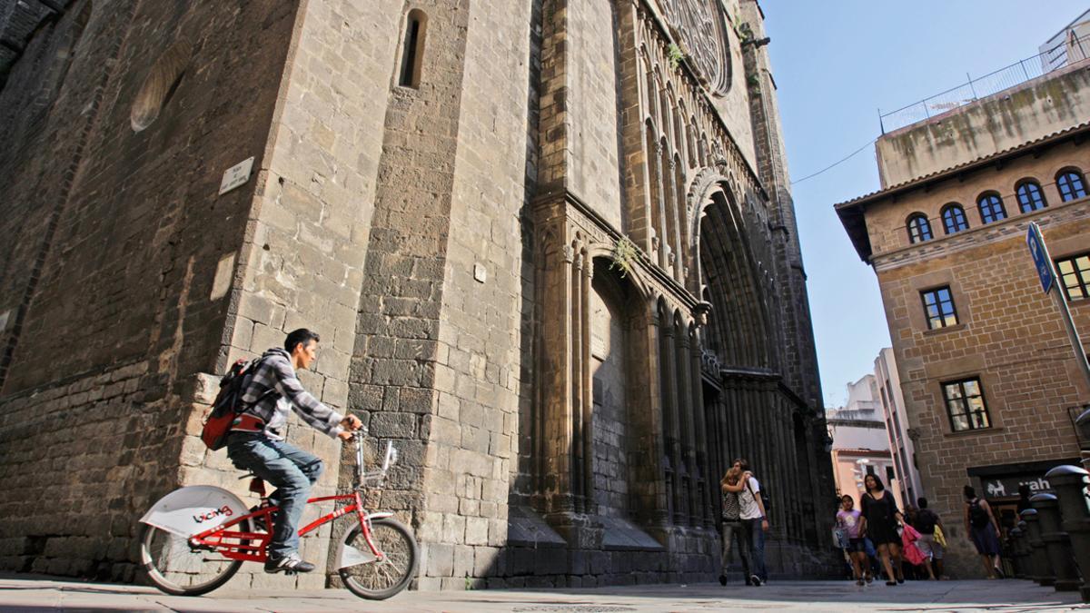 Ciclista y paseantes con la basílica de Santa Maria del Pi al fondo.