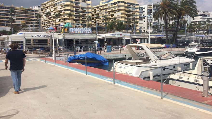 Un hombre pasea por uno de los pantalanes del puerto deportivo.