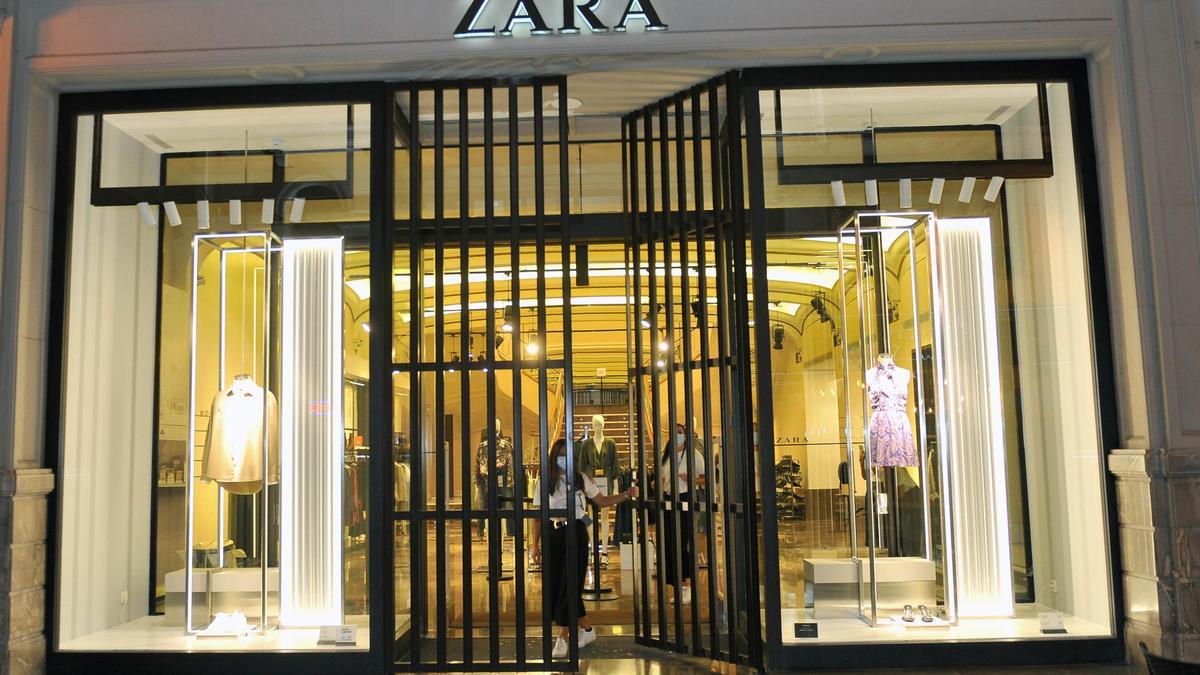 Trabajadoras de Zara cerrando la tienda  y varios clientes en el interior del establecimiento durante el último día de actividad.