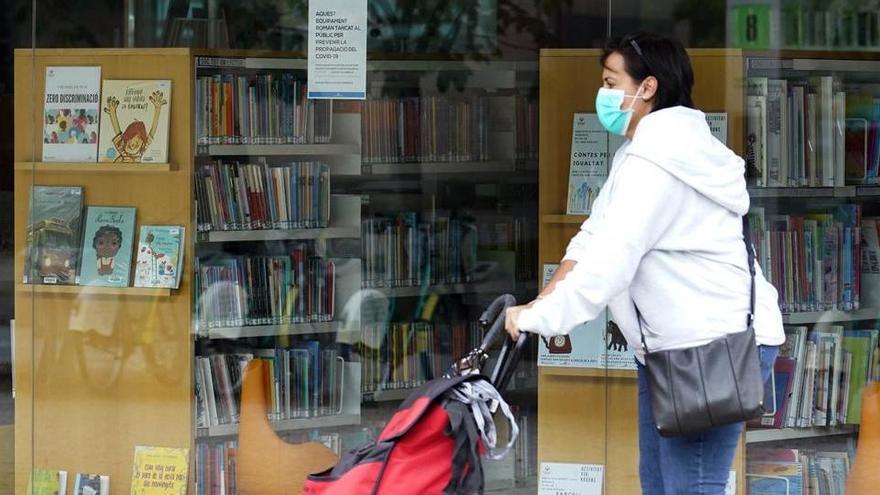 Una vianant passa per davant de la biblioteca Ernest Lluch