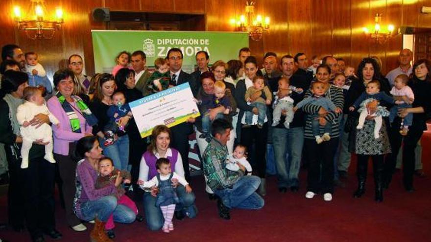 Martínez Maíllo sostiene el cheque repartido entre las familias que le acompañan en la imagen.