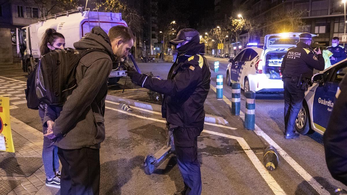 Los agentes de la Guardia Urbana de Barcelona realizan un control de alcoholemia a un conductor de un patinete que circulaba fuera del horario permitido. 