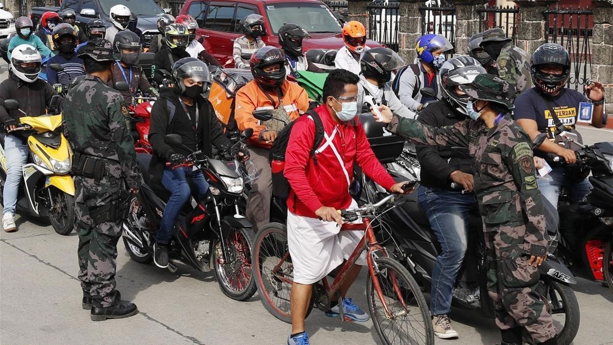 Unos policías toman la temperatura a conductores y motociclistas en Manila, este martes.
