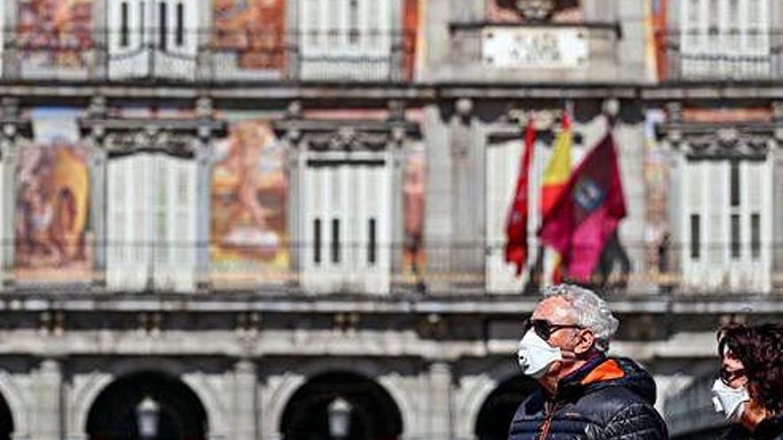 Varias personas pasean por Madrid con una mascarilla.