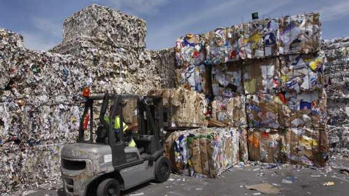 Un operario amontona las balas de papel para reciclar.