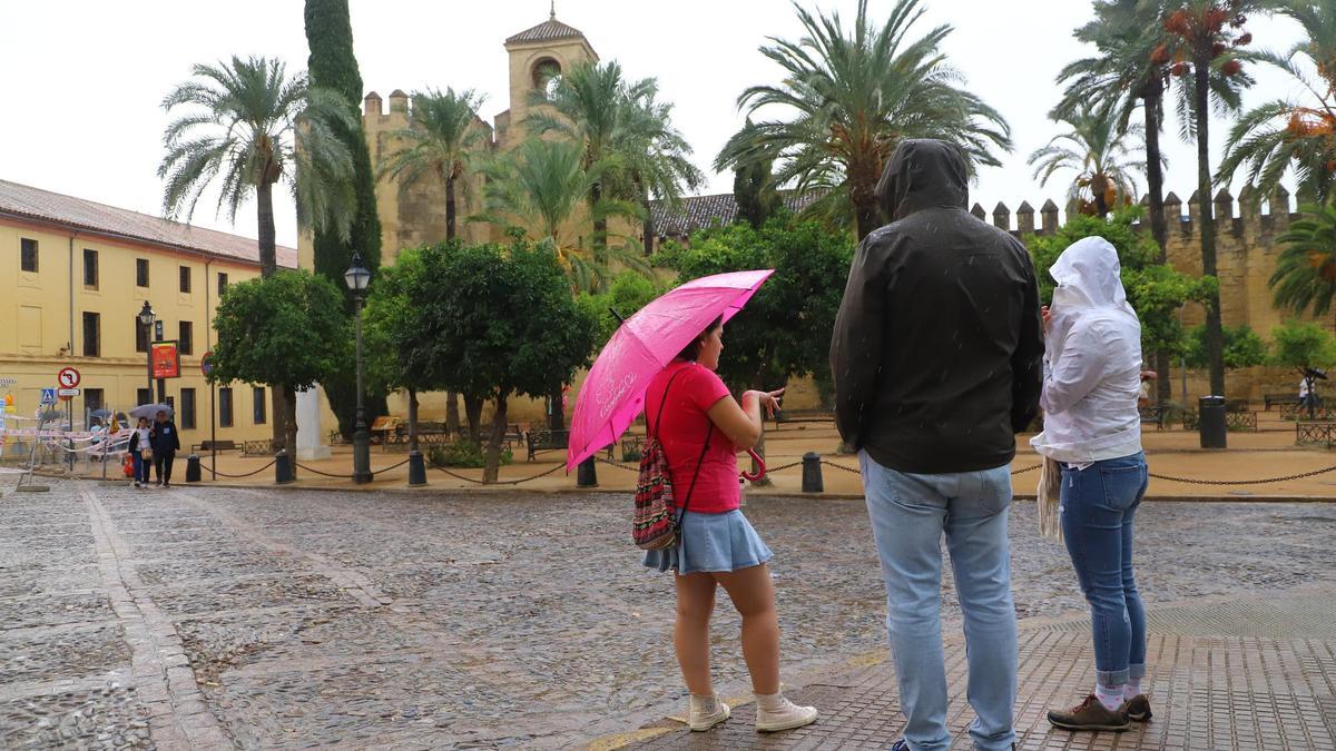 El paraguas ha acompado durante este domingo a los cordobeses. En la foto, varias personas junto al Alcázar de los Reyes Cristianos.