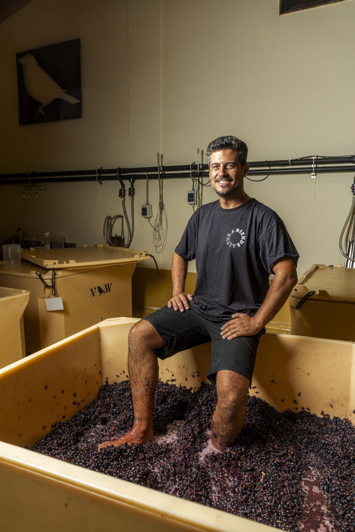 El enólogo, sonriente con los pies en las uvas.