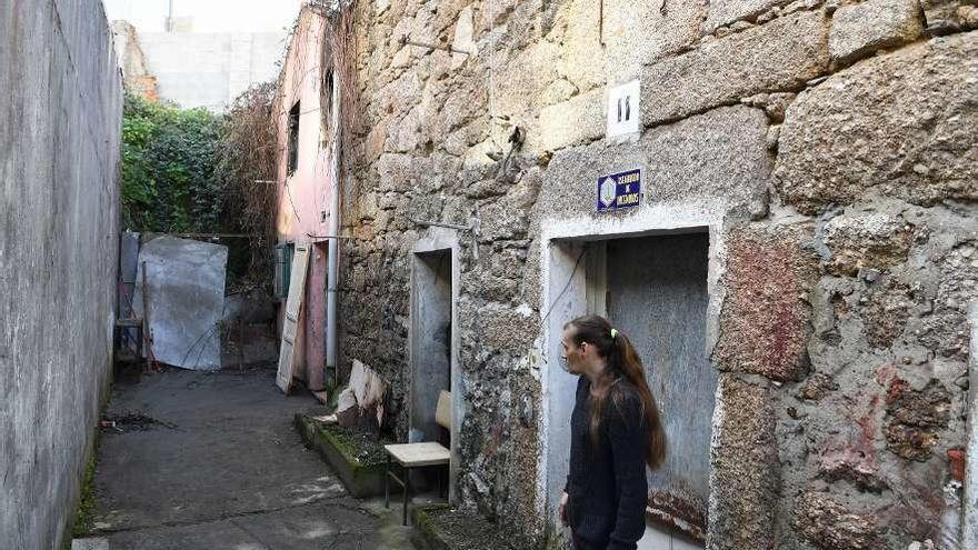 Una okupa de una de las casas de Camiño do Pinar, ayer junto a la casa que ardió el domingo, al fondo.