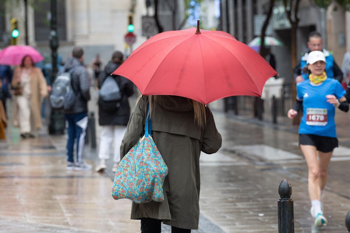 Una persona se protege de la lluvia en Zaragoza