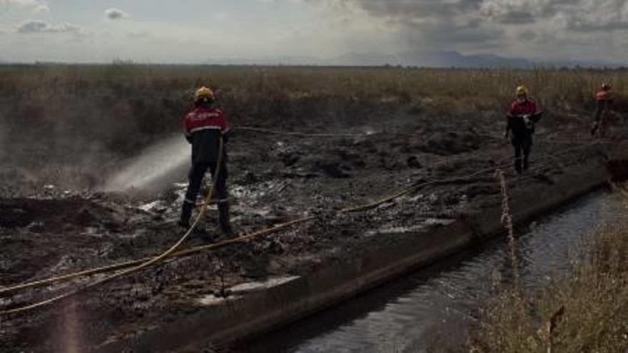 Los bomberos durante las labores de extinción del fuego declarado en torno al Parque Natural de las Salinas de Santa Pola, en las que intervino un helicóptero.