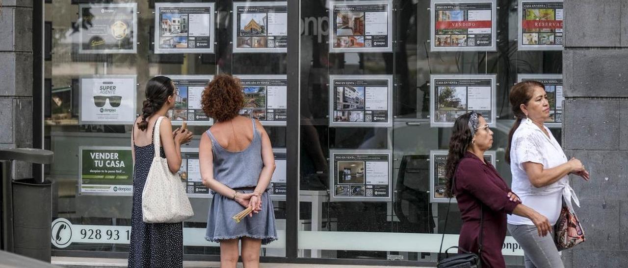 Dos personas miran los anuncios de una inmobiliaria en Las Palmas de Gran Canaria.