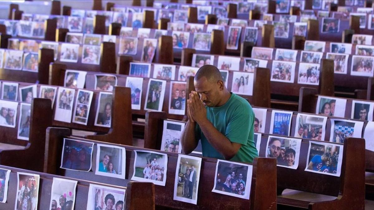 Un hombre reza el jueves santo en una iglesia de Brasilia, Brasil, en la que colocaron fotos de feligreses en los bancos vacíos
