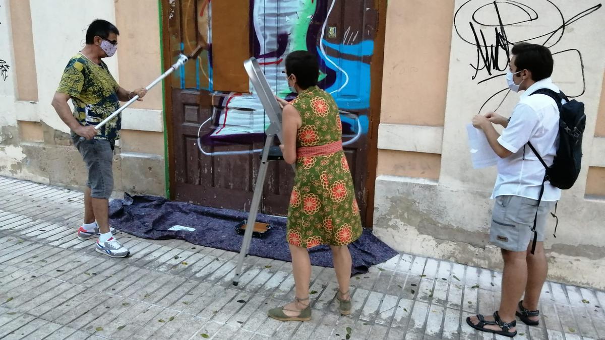 Miembros de la Plataforma quitando los grafittis de las puertas el cine