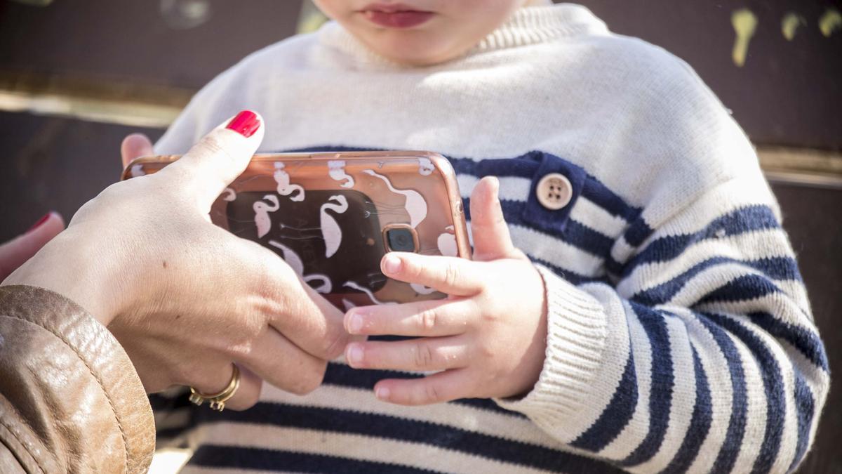 Un niño de dos años con un teléfono inteligente en sus manos