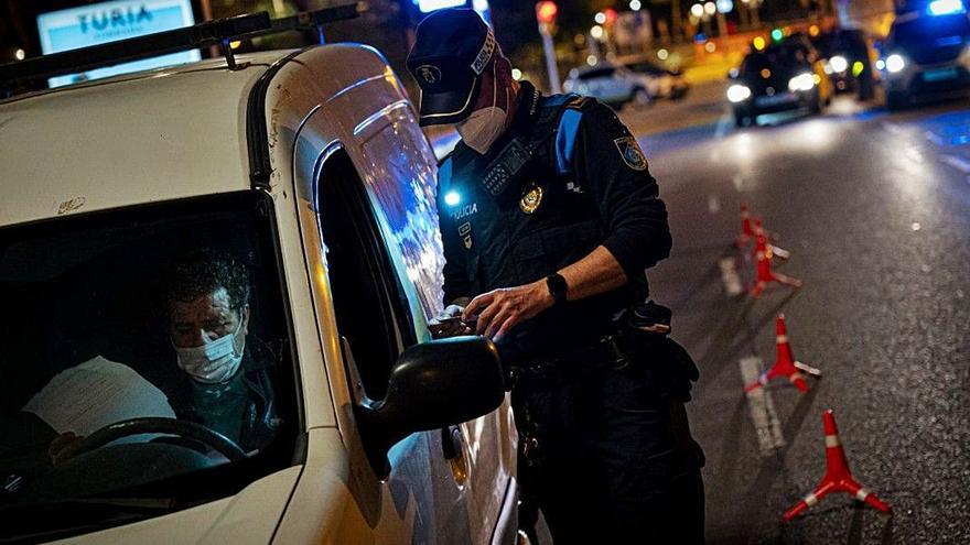 Un agente de la Policía Local comprueba la documentación de un conductor durante un toque de queda. | L.O.
