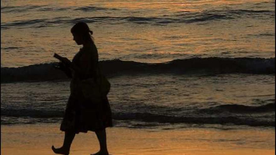 Una mujer pasea por la playa de La Concha de San Sebastián durante la puesta de sol.