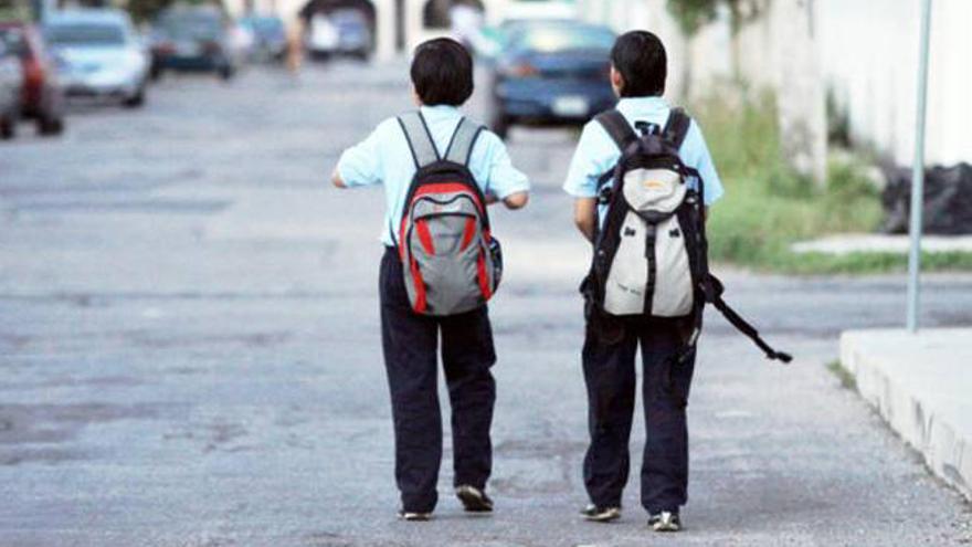 Imagen de unos niños cargados con mochila camino al colegio.