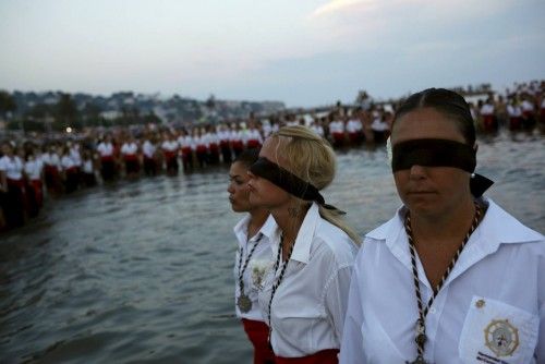 Women in traditional costumes wait for a statue of the El Carmen Virgin to be carried into the sea during a procession in Malaga