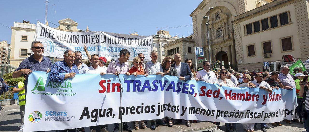Políticos socialistas y regantes tras la pancarta principal de la protesta de los agricultores.