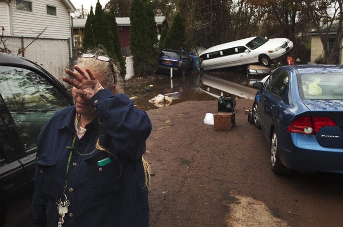 Una mujer llora tras saber que su vecino desaparecido está bien, mientras limpia su casa afectada por el huracán Sandy.