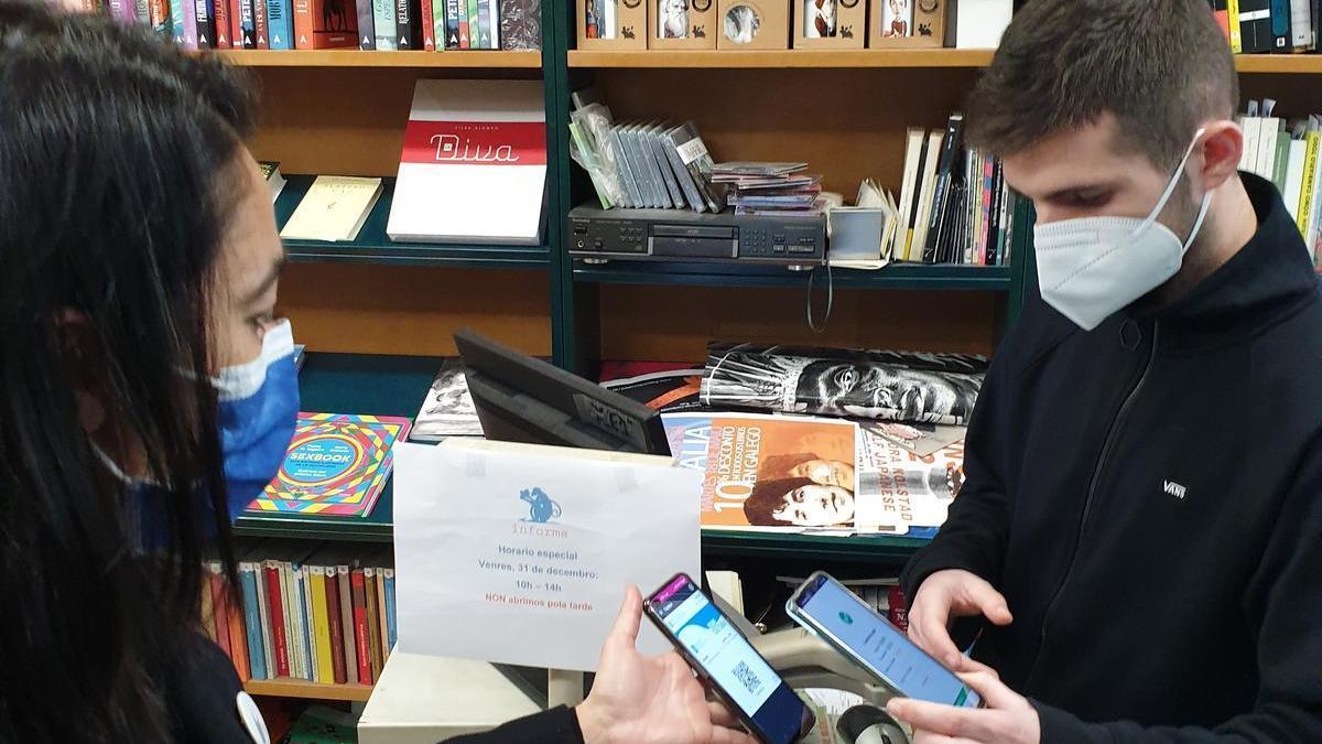 Una clienta muestra un Bono Cultura de la Xunta en una librería.