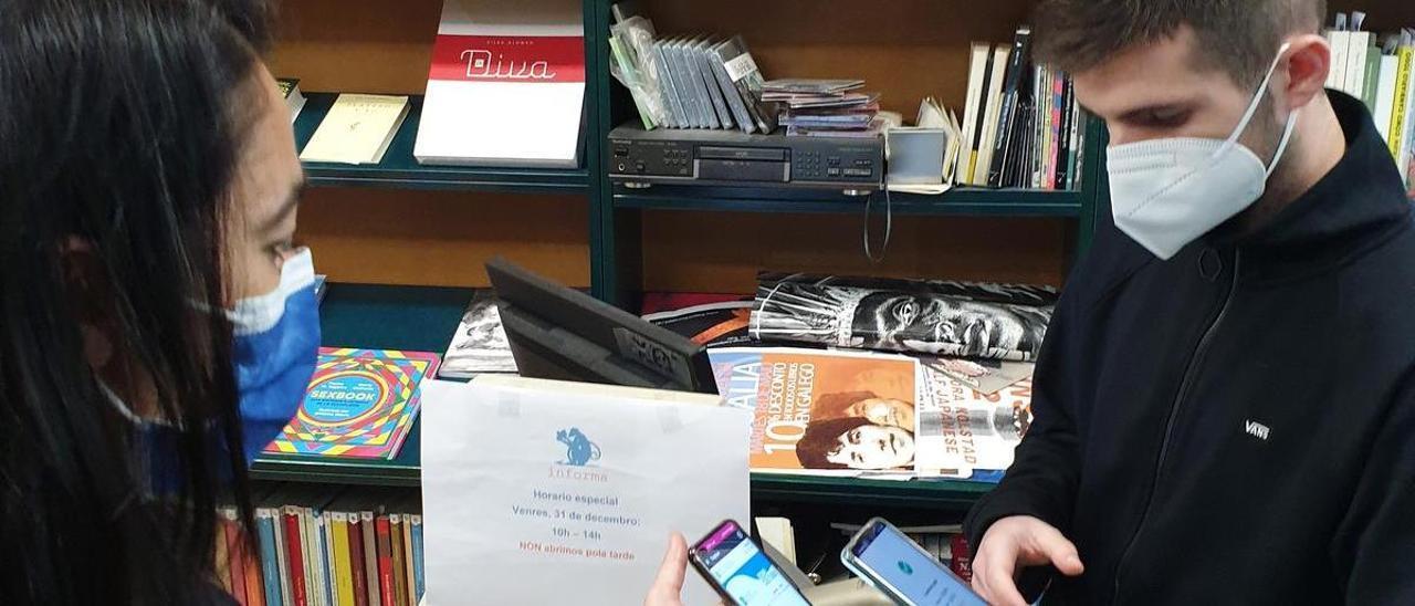 Una clienta muestra un Bono Cultura de la Xunta en una librería.