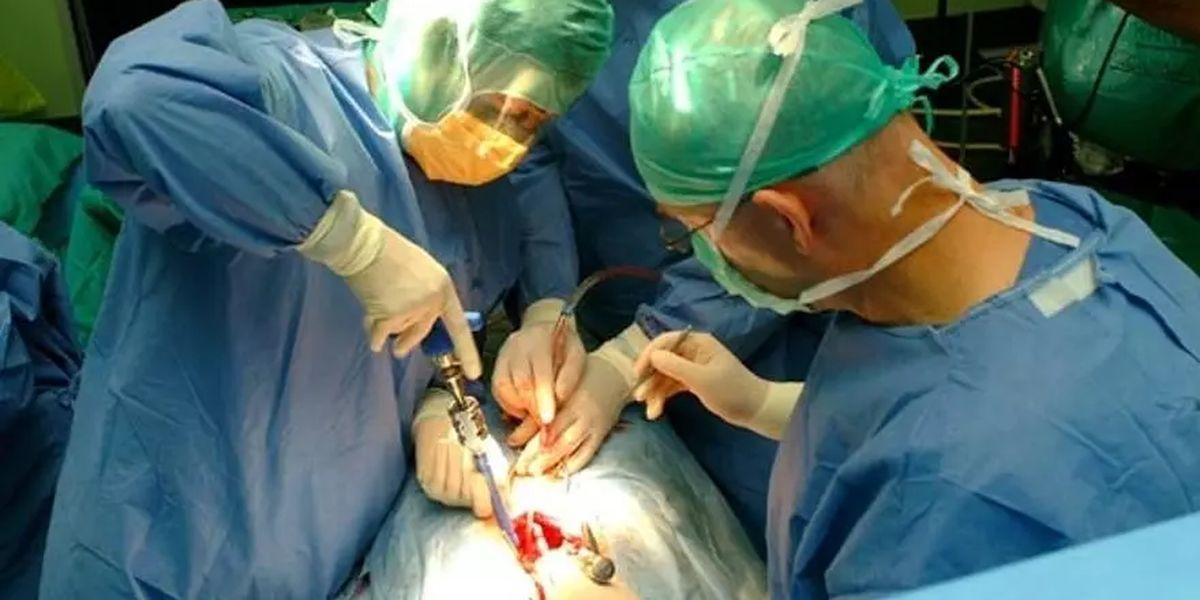 Un equip de cirurgians practica una intervenció de columna vertebral a una persona.