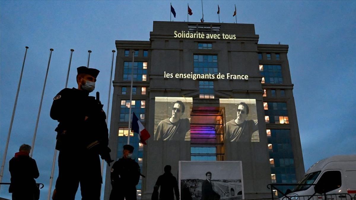 Un retrato del profesor Samuel Paty pryectado en la fachada de un hotel en Montpellier con el lema 'Solidaridad con todos los maestros de Francia'.