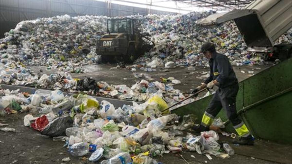 Un empleado trabaja con residuos en las instalaciones de la planta de tratamiento y selección de envases de Gavà, para su posterior reciclaje.