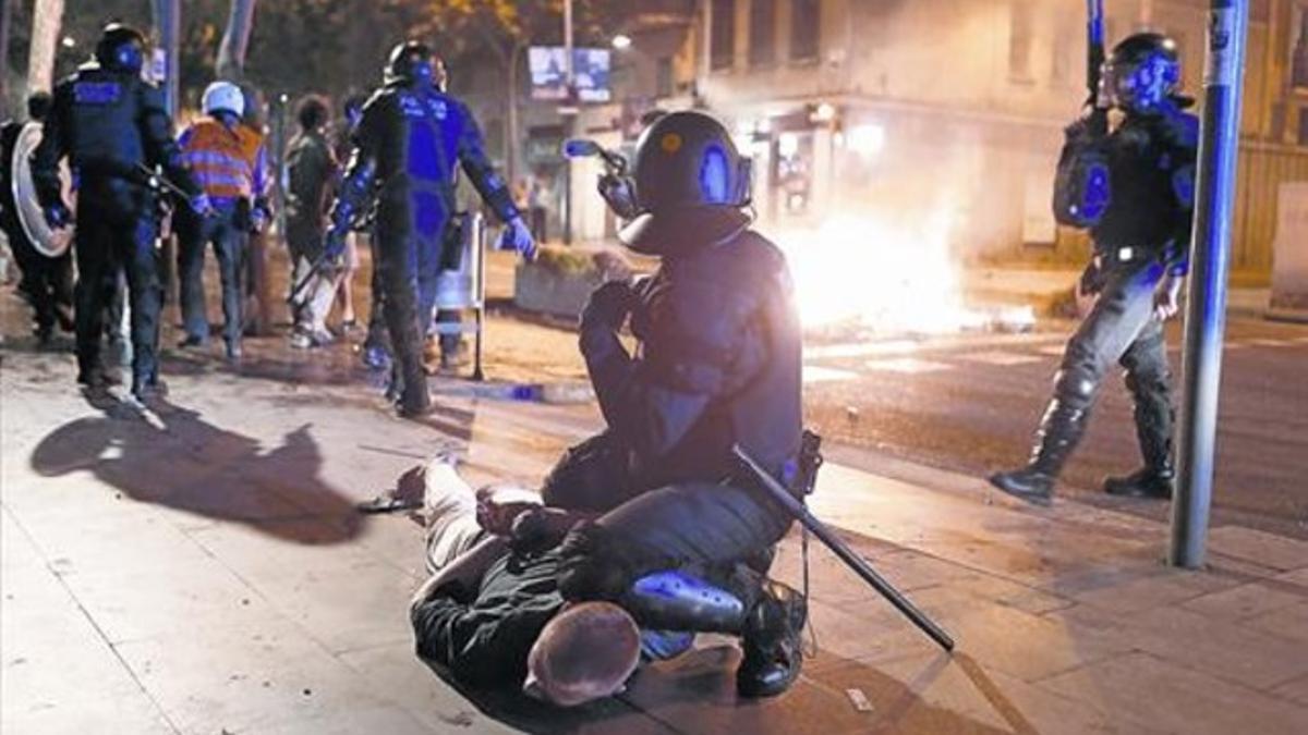 Un mosso reduce a uno de los jóvenes detenidos durante la semana de disturbios en el barrio de Sants, a finales de mayo del año pasado.