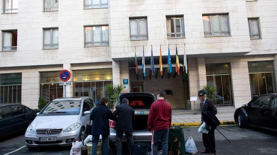 Una familia de turismo en Avilés saca el equipaje del coche delante de un hotel de la ciudad.