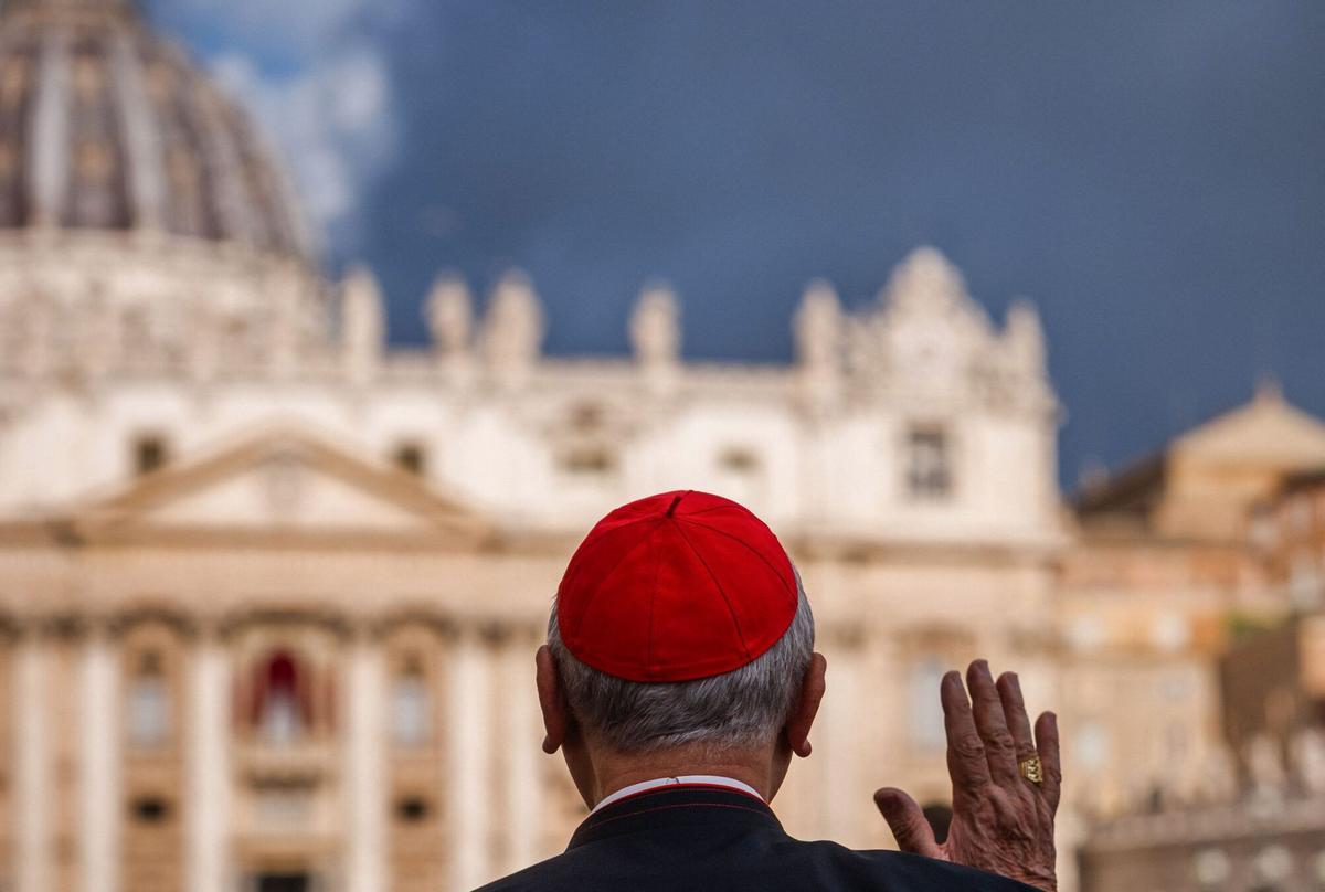 A cardinal gestures as he arrives for a congregation meeting at the Vatican with a view of the St Peters Basilica in the background on May 6, 2025. (Photo by Dimitar DILKOFF / AFP)