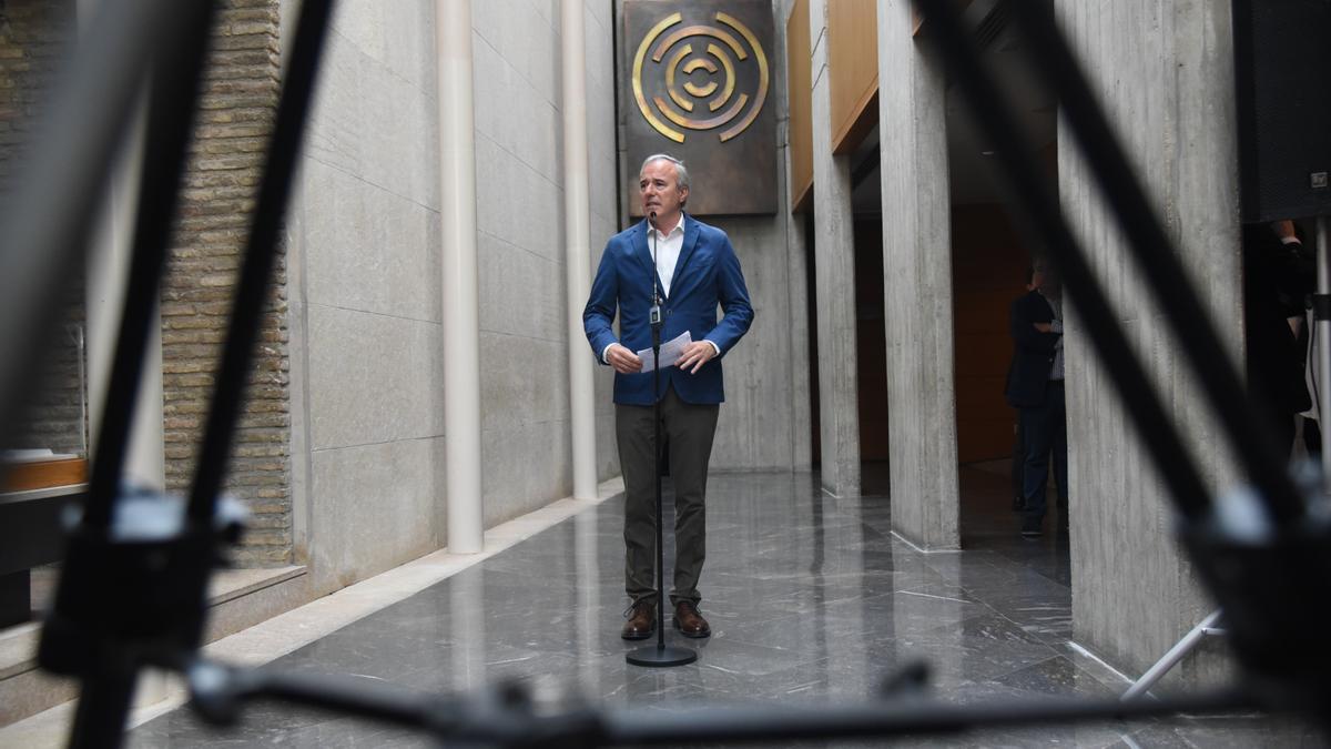 Jorge Azcón, visto bajo un trípode de una cámara de televisión en el hall de las Cortes de Aragón.