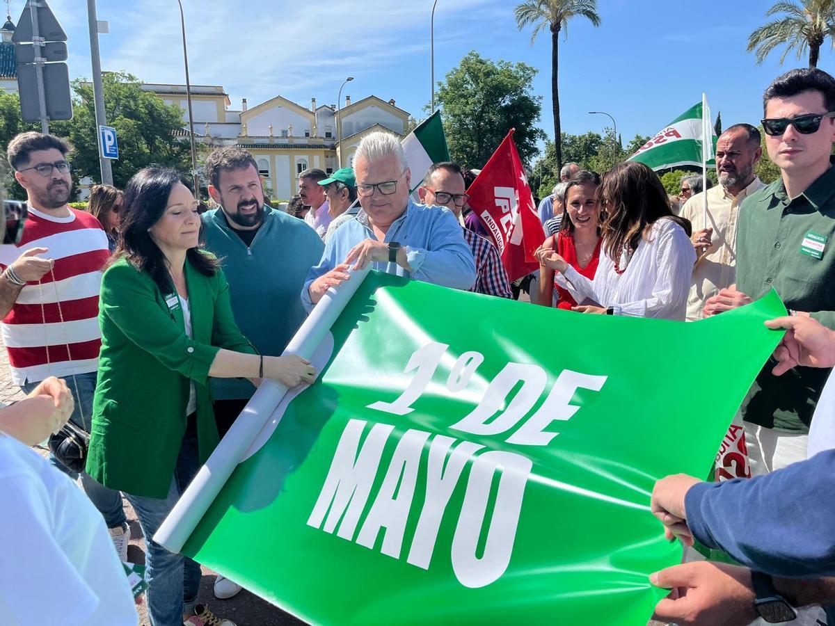 Rafi Crespín despliga la pancarta del PSOE para el 1 de mayo hoy en Córdoba.