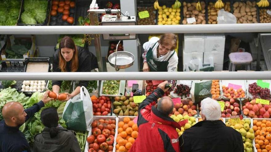 Clientes en un puesto de fruta en el mercado de San Agustín.