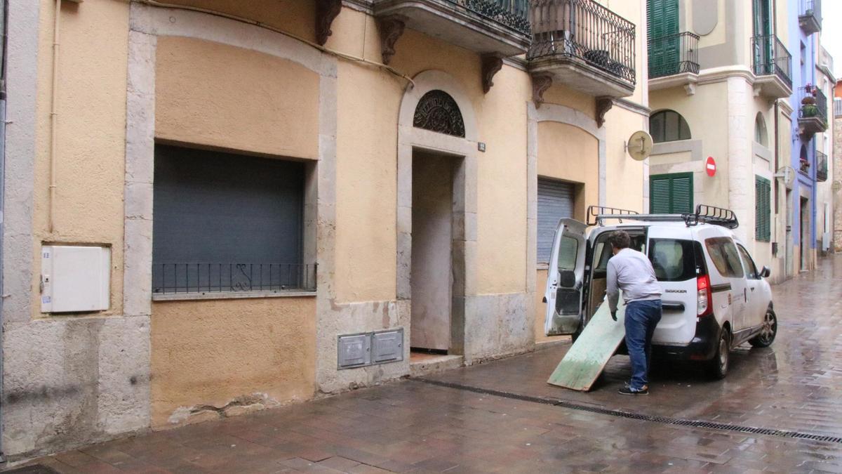 Un constructor descarregant el material davant l'edifici on s'ha desprès un tros de sostre a Llagostera.