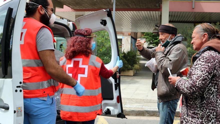 Voluntaris de la Creu Roja distribuint aliments a persones sensesostre a Girona