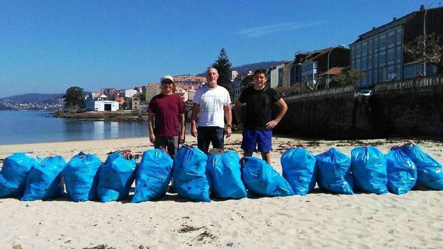 Voluntarios con los 13 sacos de basura recogidos en el arenal. // S.Á.