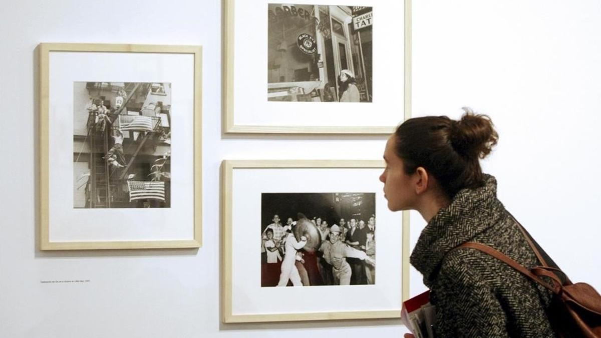 Una mujer contempla fotografias de Arthur Fellin  Weegee   arquetipo del fotografo de prensa del siglo XX