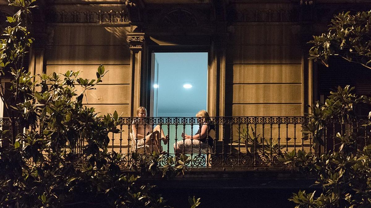 Dos mujeres leen en el balcón de su casa, en Gran de Gràcia