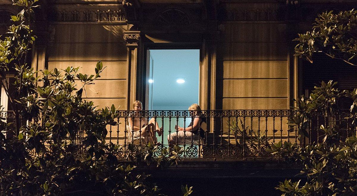 Dos mujeres leen en el balcón de su casa, en Gran de Gràcia.