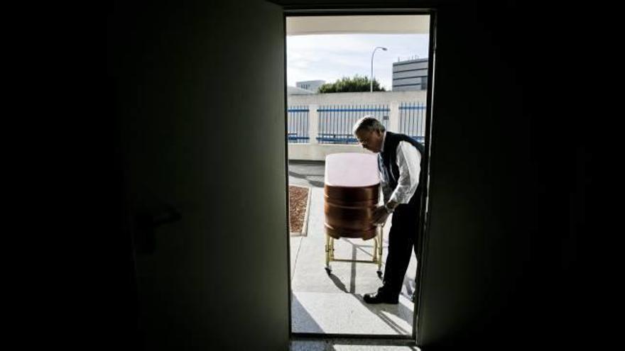 Al finalizar un sepelio, un trabajador de un tanatorio introduce un féretro en las instalaciones del crematorio para ser incinerado.