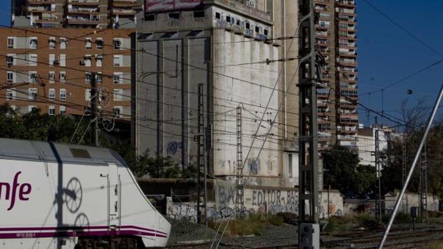 El edificio de las antiguas harineras Magro, en primer término, al borde de las vías del tren junto al paso a nivel del barrio de San Blas.