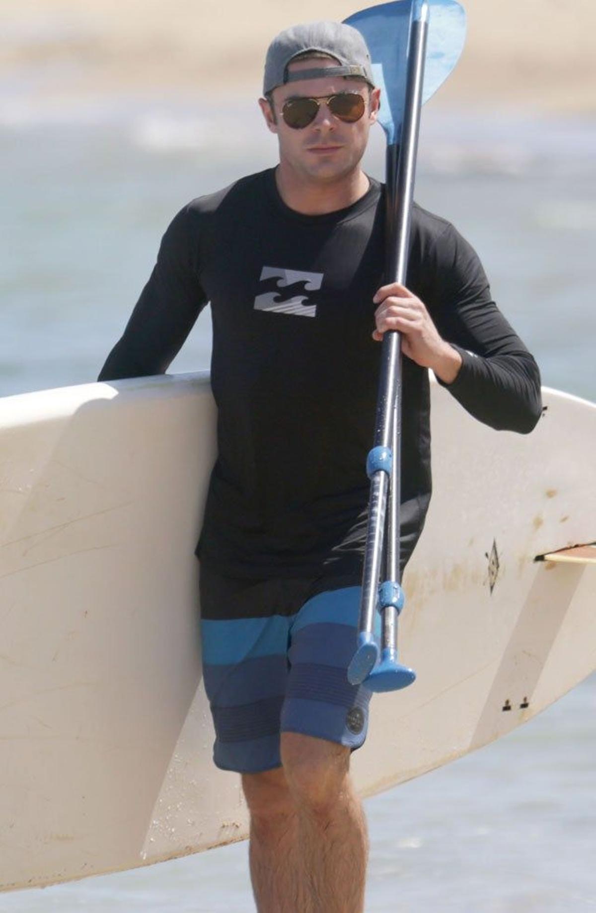 Zac Efron de paseo por la orilla con la tabla y la pala