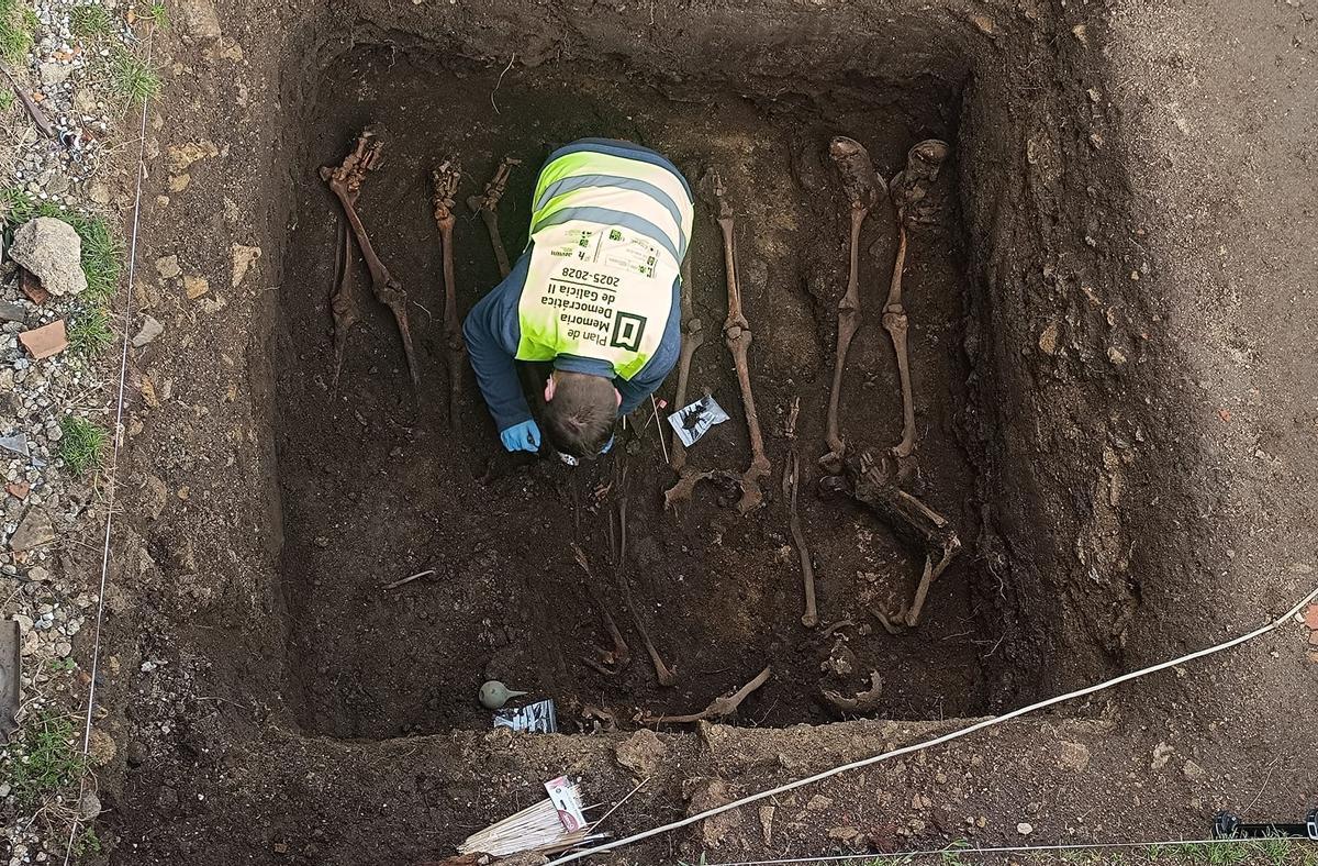 Un arqueólogo limpia los restos encontrados en la fosa común de Luou